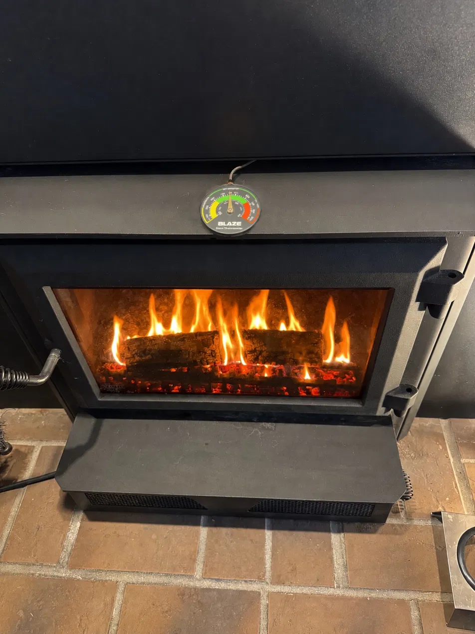 A wood stove at full secondary combustion, flames filling the firebox