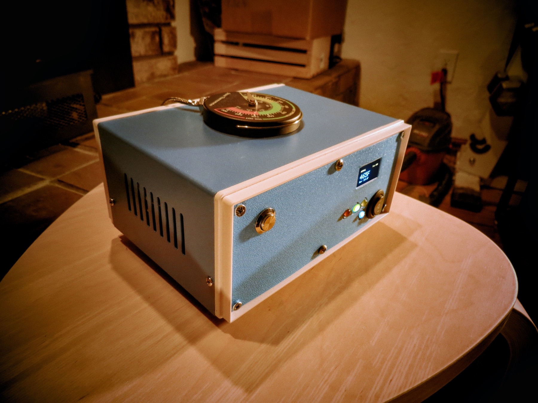 A finished stoveLogic unit in warm firelight, analog thermometer on top
