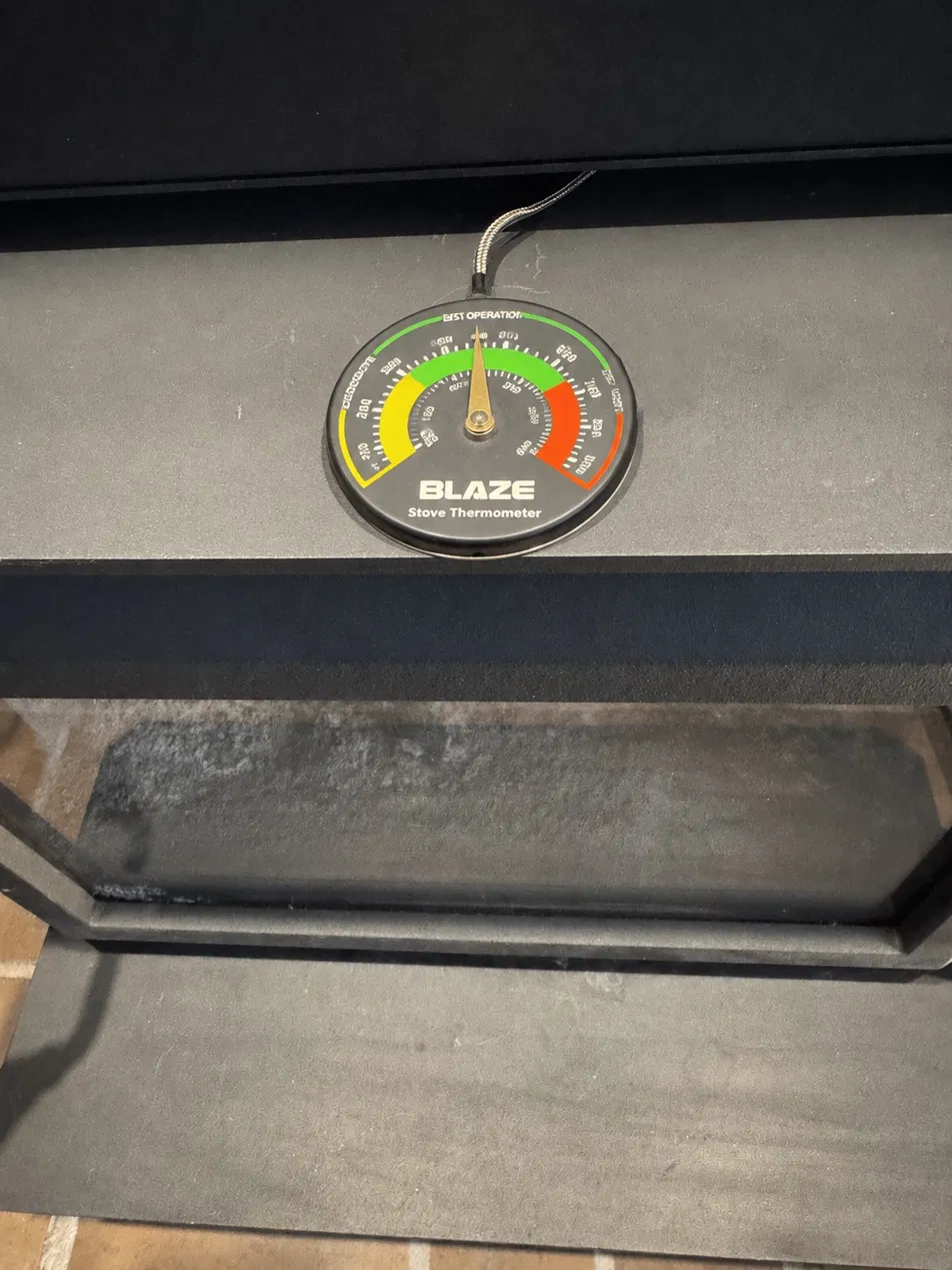 The BLAZE magnetic stove thermometer with a braided steel cable, mounted on the stove surface